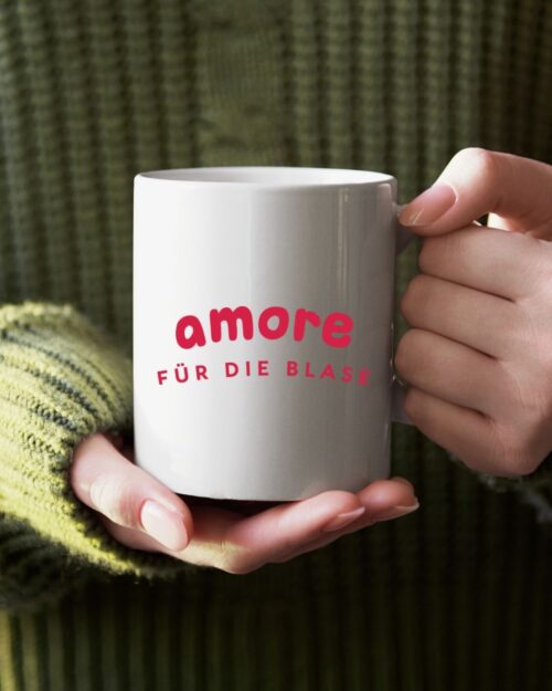 weiße tasse in der hand einer frau mit grünen pulli